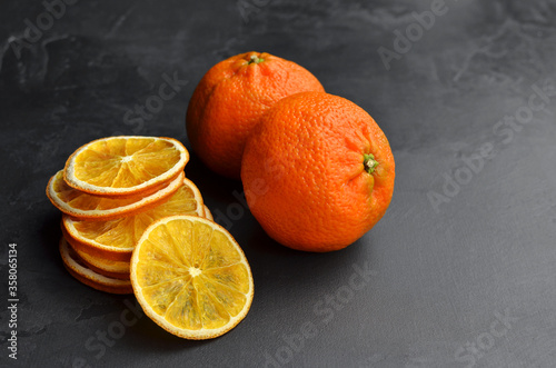 Dry orange slices and fresh cittrus fruits on dark slate background photo