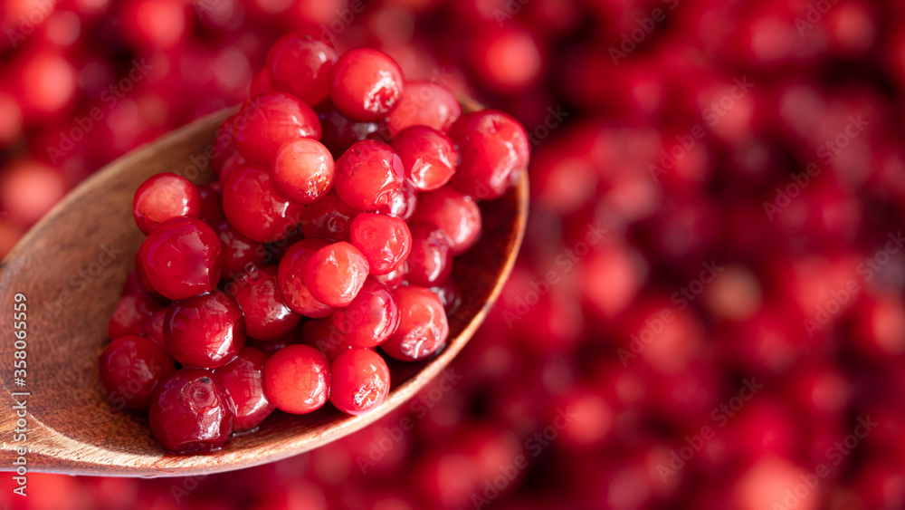 Cranberry placed in a wooden spoon and placed on a wooden floor,  Red sour fruit  There are many health benefits.