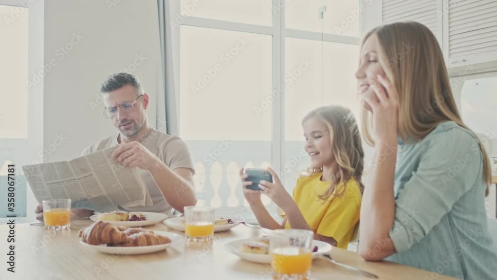 A good-looking young family is spending time in the kitchen while eating breakfast at home in the morning A good-looking young family is spending time in the kitchen while eating breakfast at home in the morning