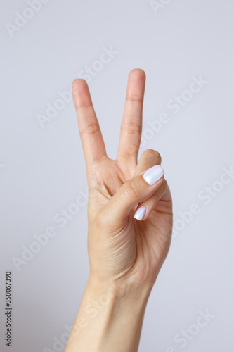 Gesture and sign, female hand on a white background. Fingers showing peace or victory