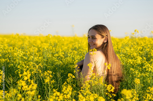 Beautiful girl in a rapeseed field, with an open shoulder. © Artsiom P