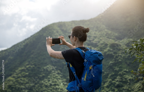 Woman hiker using smartphone on forest mountain top