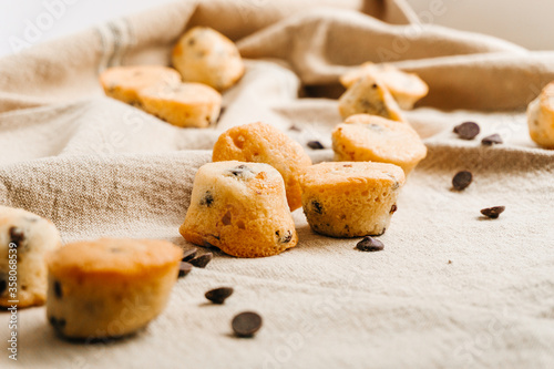 Several little Chocolate chips muffins with some chocolate chips and muffins on the background. Tasty and sweet concept.