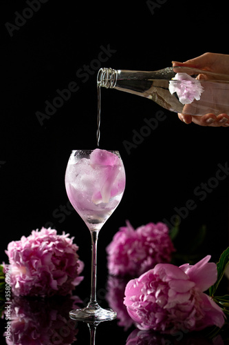 Flavoured gin and tonic in a tall glass  with peon flowers background