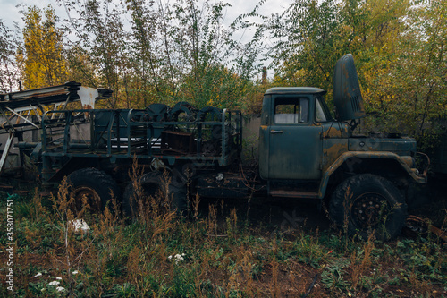 Old rusty truck at abandoned overgrown industrial area
