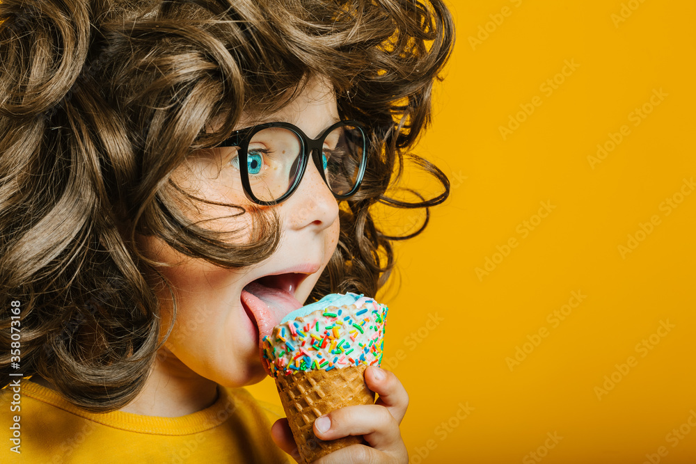 boy with long hair happily eats ice cream