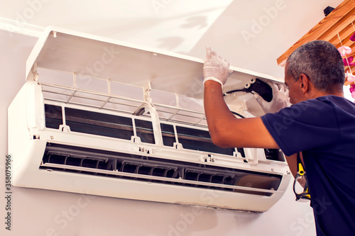 Man worker fixing air conditioning on the wall. photo