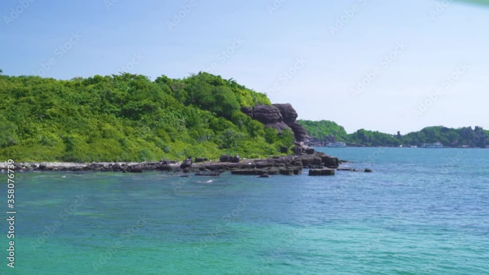 Scenic Island with green lush rocky cliffs and blue pristine ocean water. Green tropical isalnd with rocky coastline, turquoise water. Summer and nature concept. Scenic Island with green lush rocky cliffs and blue pristine ocean water. Green tropical isalnd with rocky coastline, turquoise water. Summer and nature concept.