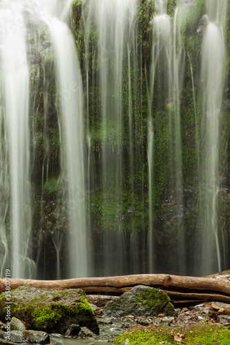 Beautiful view of the taiga waterfall with a log and stones in the foreground  background of washed-out water.