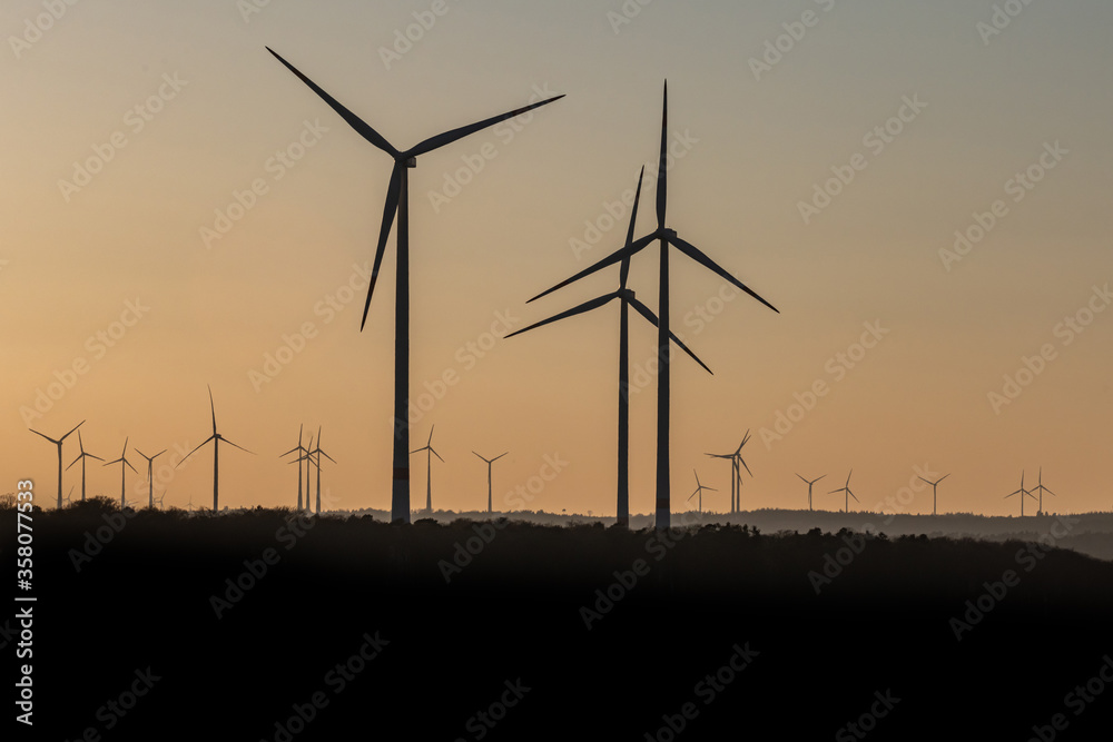 Obraz premium Black Silhouette of windturbines energy generator on amazing sunset at a wind farm in germany