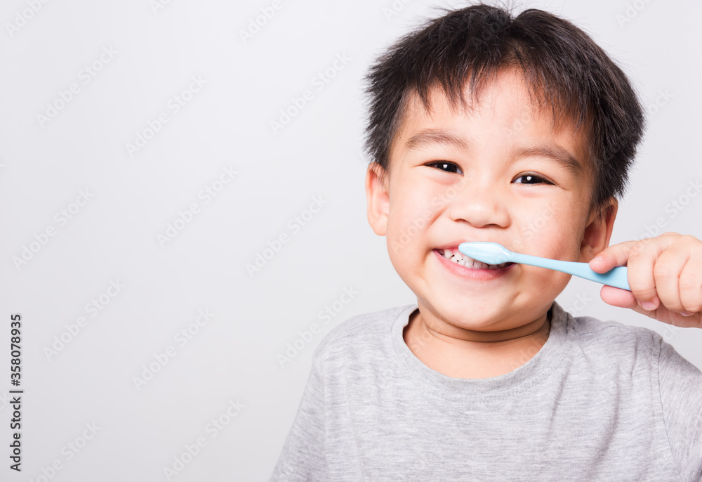 Closeup Asian face, Little children boy hand holds toothbrush he brushing teeth myself on white background with copy space, health medical care Closeup Asian face, Little children boy hand holds toothbrush he brushing teeth myself on white background with copy space, health medical care
