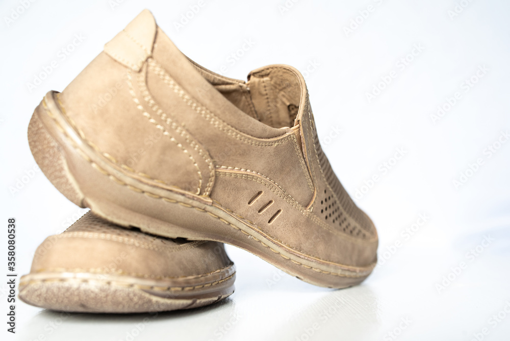 Men's beige leather shoes, models moccasins. Photographed close-up on a light background. Men's beige leather shoes, models moccasins. Photographed close-up on a light background.