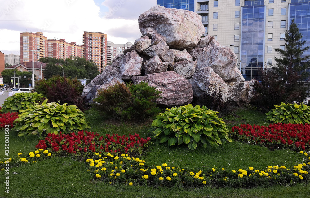 Composition of large stones on a flower bed surrounded by plants