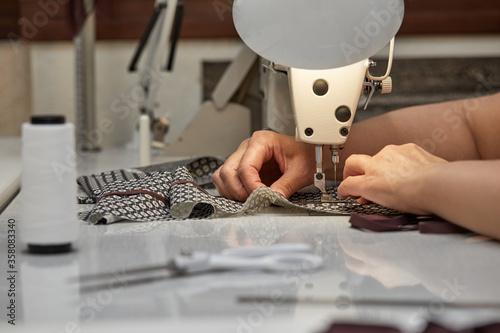 girl seamstress sew on the sewing machine. Women's hands sewing on the sewing machine