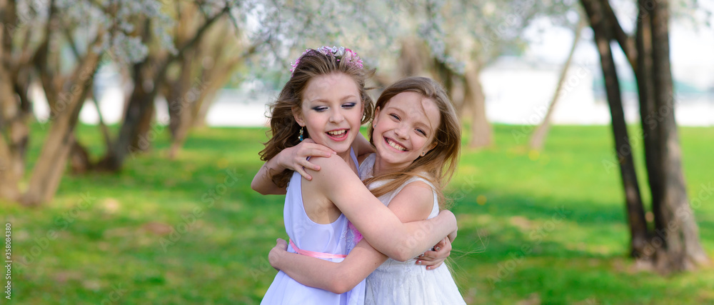 Beautiful young girls with blue eyes in a white dresses in the garden with apple trees blosoming having fun and enjoying smell of flowering spring garden. Beautiful young girls with blue eyes in a white dresses in the garden with apple trees blosoming having fun and enjoying smell of flowering spring garden.