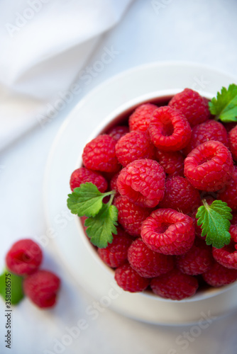 Fresh raspberries with leaves in white cup