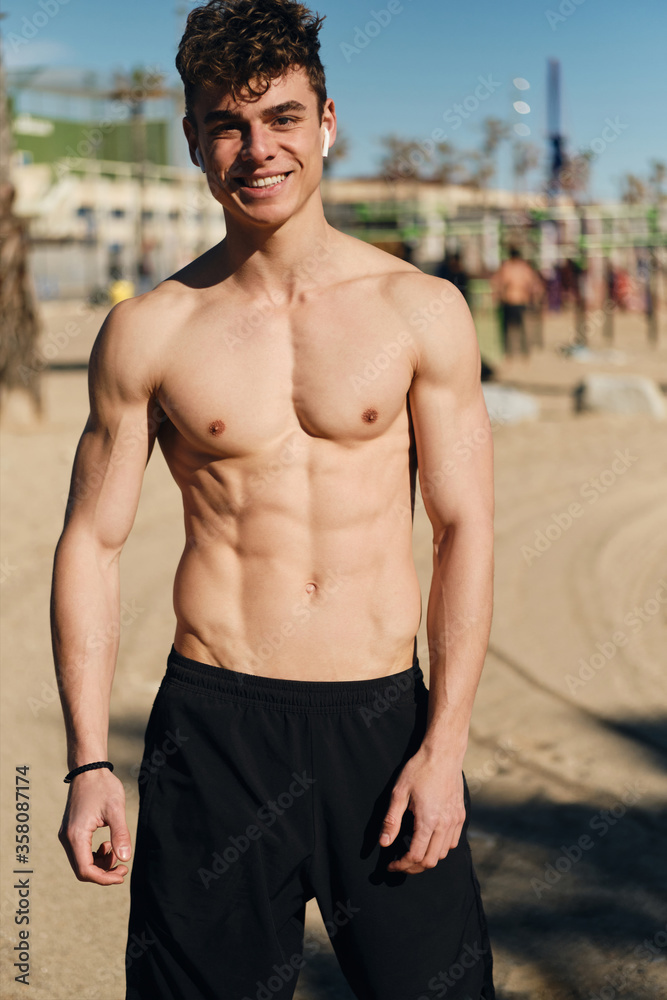 Young cheerful man with naked torso happily looking in camera after workout outdoor Young cheerful man with naked torso happily looking in camera after workout outdoor