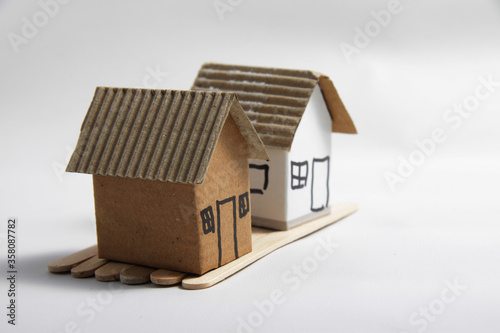 Brown cardboard home miniature on a white isolated background, represented redisential and investment ideas photo