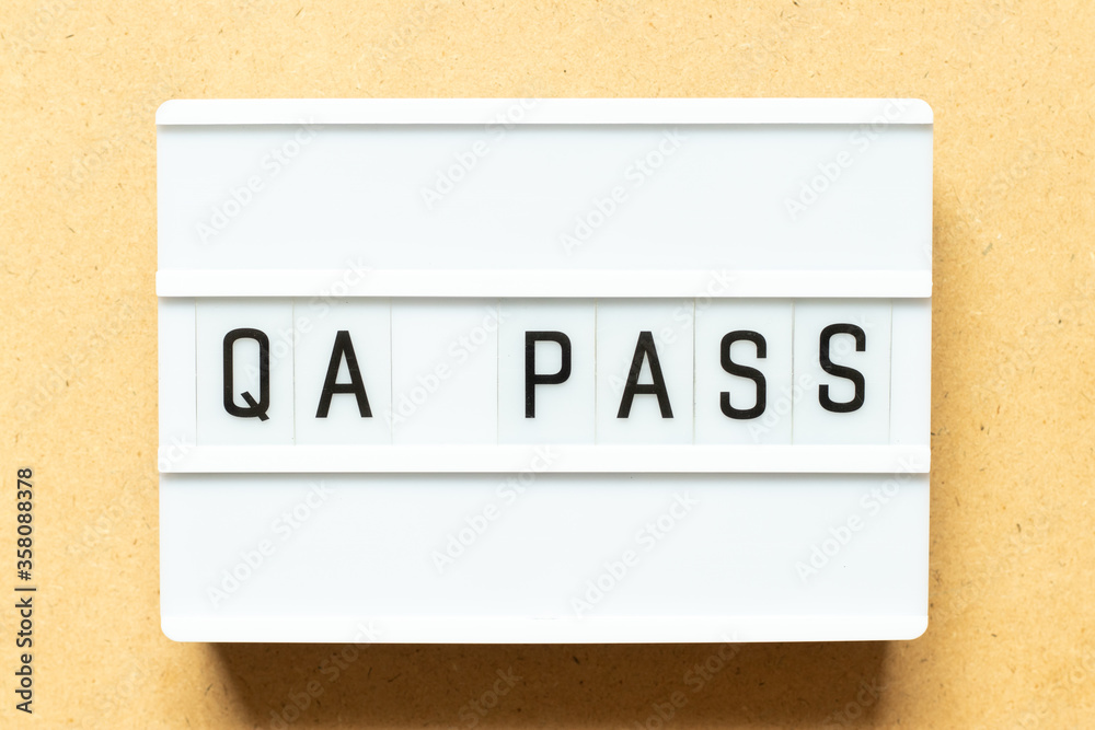 Lightbox with word QA (Abbreviation of Quality Assurance) pass on wood background Lightbox with word QA (Abbreviation of Quality Assurance) pass on wood background