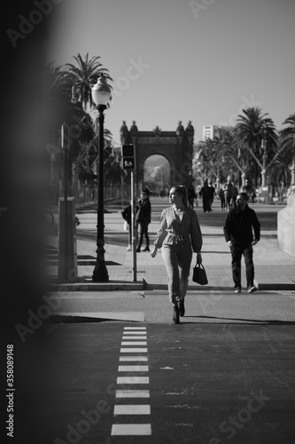 Young posh stylish woman confidently crossing the road along beautiful city street. Black and white