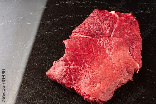 Steak raw. Barbecue Rib Eye Steak or rump steak on black stone
