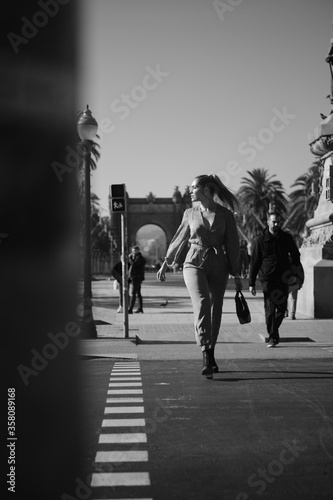 Young beautiful stylish woman walking along city street. Black and white