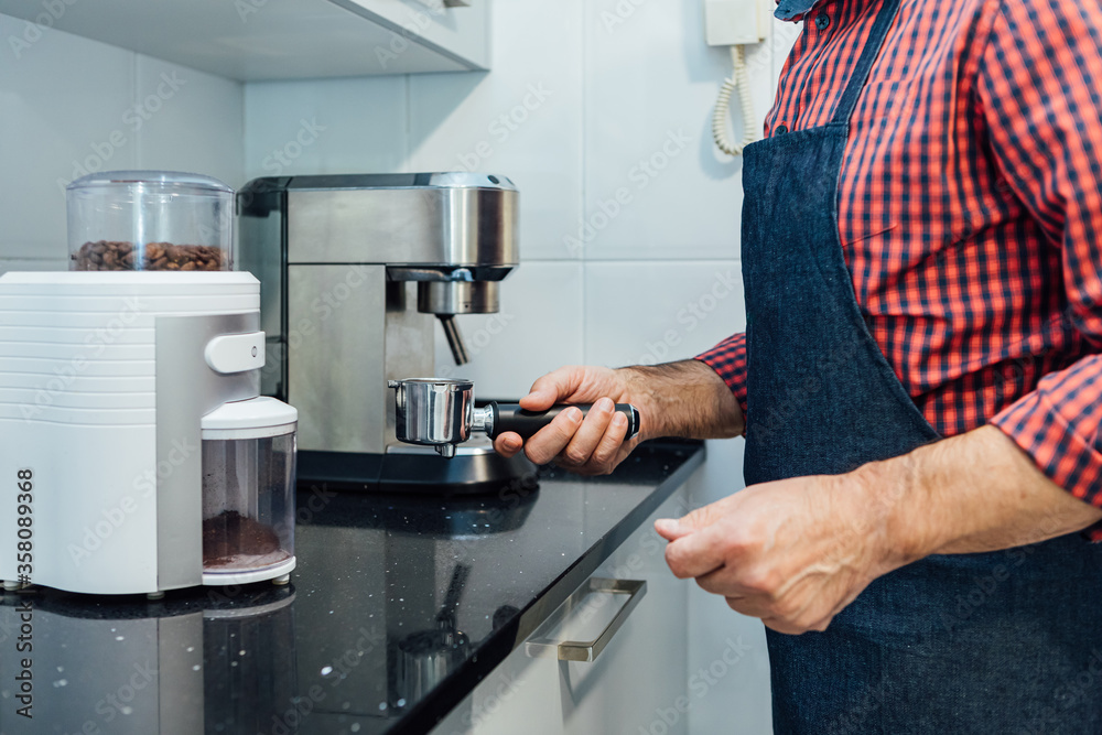 Man wearing plaid shirt and apron preparing an espresso Man wearing plaid shirt and apron preparing an espresso