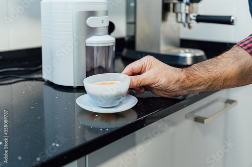 Detail of man's hands holding a cup with espresso coffee