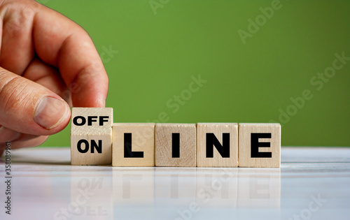 The hand turns the wooden cube and changes the word ONLINE to OFFLINE