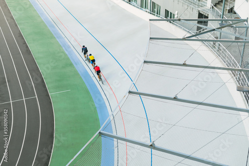 Three cyclists train on the velodrome, top view. Professional cyclists ride on the bike path, top view. Cycling. Track bike. Athletes ride a track bike. Recreation. photo