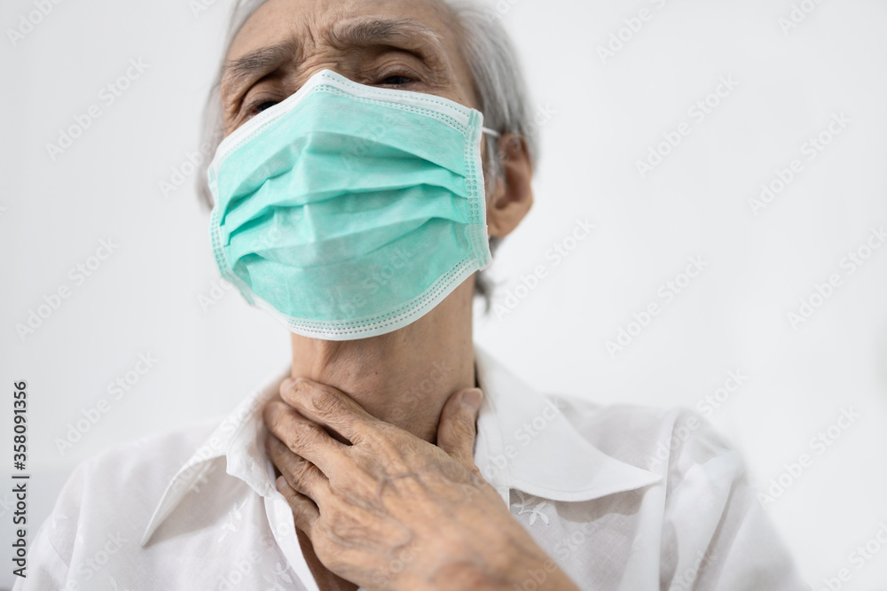 Hands touching neck,sick senior female wearing protective face mask,old