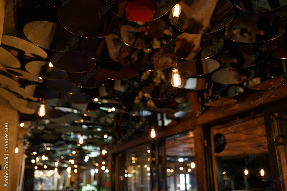Stylish abstract bar interior. The ceiling is decorated with small round mirrors.