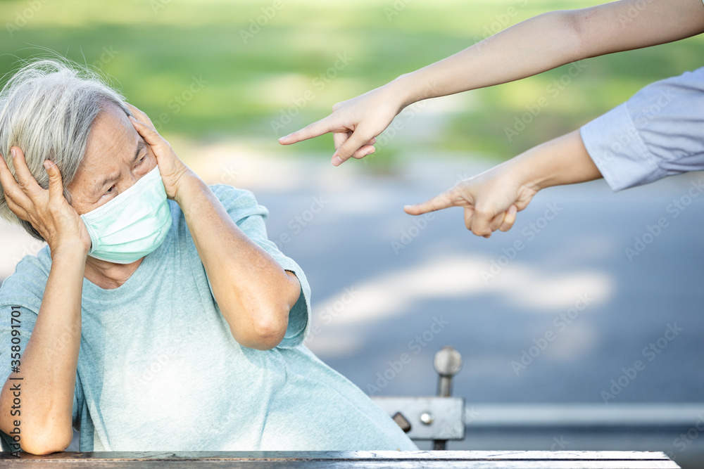 Sad asian senior woman wearing face mask during the pandemic of Coronavirus or Covid-19,hands pointing fingers to old elderly in a mask,bullying victim and hate,she is not a virus,bullied by society Sad asian senior woman wearing face mask during the pandemic of Coronavirus or Covid-19,hands pointing fingers to old elderly in a mask,bullying victim and hate,she is not a virus,bullied by society