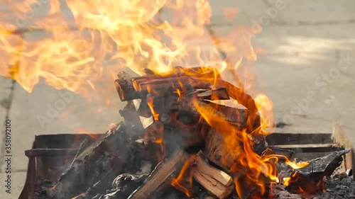 Birch firewood burns in a barbecue grill. Sunny spring day. Nobody. Picnic on a site near the house. Charcoal fire barbecue