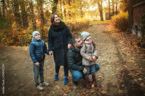 Parents and children walk in the autumn park, they saw something upstairs and look there. Soft focus