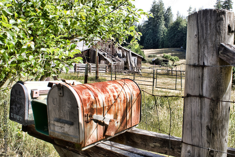 Fototapeta premium Old rusted rural metal mailboxes neat a farm field