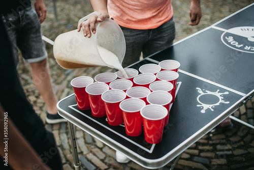 Obraz na płótnie Hand refelling beer pong activity cups on a ping pong table