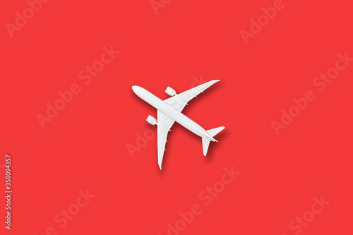 Model white plane, airplane on red color background with copy space, Flat lay design travel concept on red background. top view model air plane on red color background.