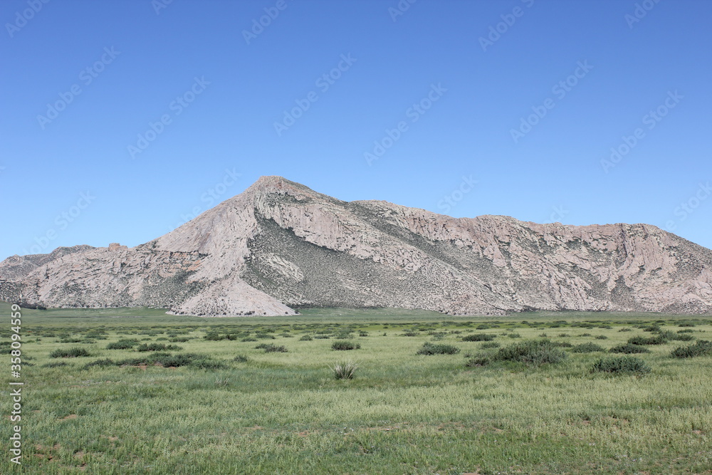 Fototapeta premium Large gray rocky mountains amid the blue sky
