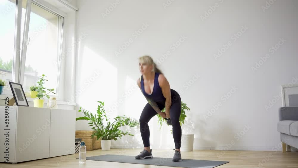 Athletic woman at home doing kettlebell swing exercise Athletic woman at home doing kettlebell swing exercise