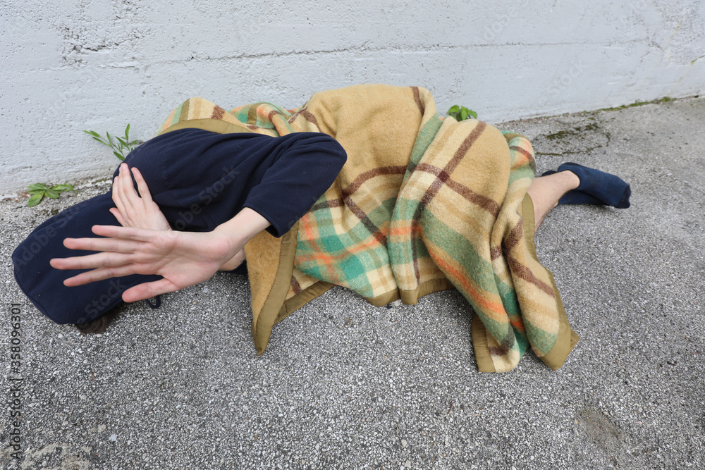 Foto de homeless man sleeps on the street on the asphalt under a dirty