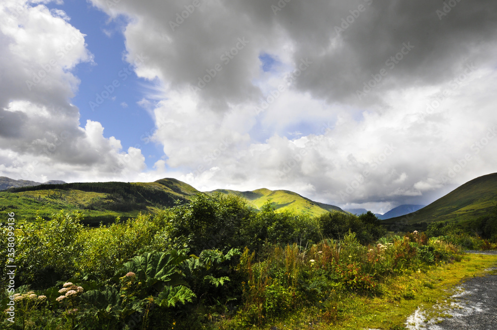 Obraz premium Magnifique vue panoramique sur les monts et les collines dans un val à l'embouchure d'un bras de mer en Irlande. Ciel orageux, verdure et clair-obscur.