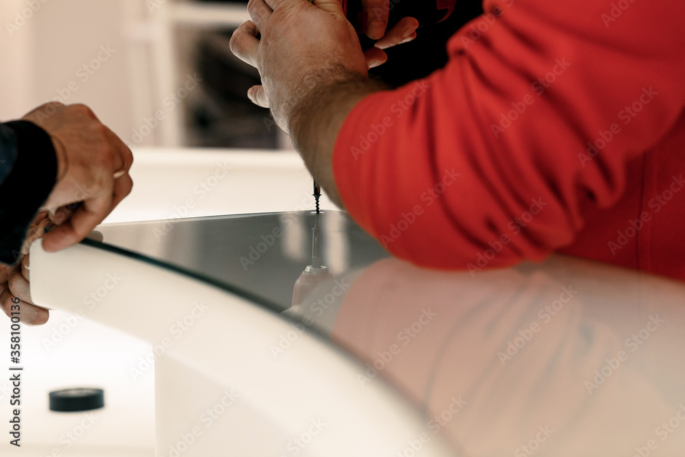 screw in the screwdriver. builders work in a restaurant. build a bar counter of glass. hands close-up screw in the screwdriver. builders work in a restaurant. build a bar counter of glass. hands close-up
