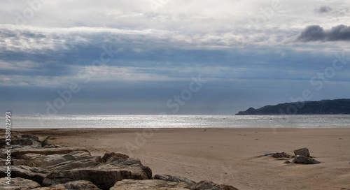 Leerer Strand in Spanien mit dicken Wolken und Spiegelung auf dem Wasser