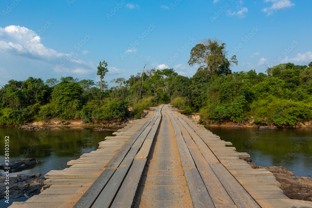 Wooden rustic bridge over river in dangerous dirt road in the amazon rainforest, Brazil. Driver POV. Concept of transport, logistics, travel, ecology, danger, off road and co2.