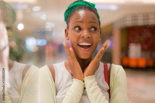 young beautiful and happy afro American girl at buying shopping mall - lifestyle portrait of millennial black girl enjoying looking clothing at beauty fashion store