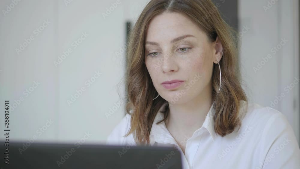 Close-up, caucasian woman with green eyes works behind a laptop. Close-up, caucasian woman with green eyes works behind a laptop.