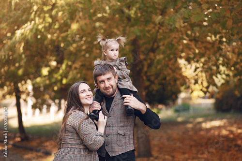 Family in a autumn park. Woman in a brown dress. Cute little girl with parents © hetmanstock2