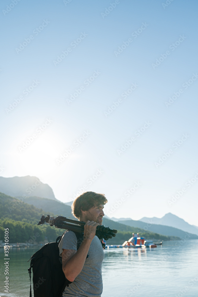 Fototapeta premium Profile view of a young male photographer standing by calm morning sea