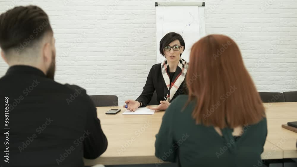 Attractive businesswoman, teacher or mentor coach speaking to young people, woman in glasses teaching audience at training seminar, female business leader speaker talking at meeting Attractive businesswoman, teacher or mentor coach speaking to young people, woman in glasses teaching audience at training seminar, female business leader speaker talking at meeting